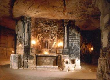 Oud, sierlijk altaar in een slecht verlichte Fluweelengrot met kaarsverlichting en gedetailleerd houtsnijwerk.